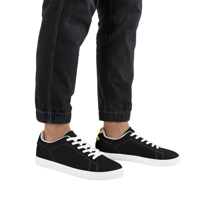 All-black Jamaica flag Ackee Walkers low top sneakers with black laces, black outsole and a green and gold Jamaican flag chevron at the heel