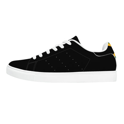 All-black Jamaica flag Ackee Walkers low top sneakers with black laces, black outsole and a green and gold Jamaican flag chevron at the heel