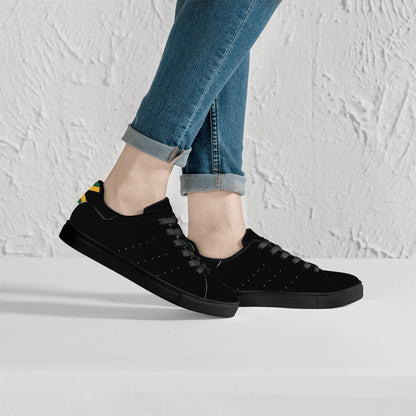 All-black Jamaica flag Ackee Walkers low top sneakers with black laces, black outsole and a green and gold Jamaican flag chevron at the heel