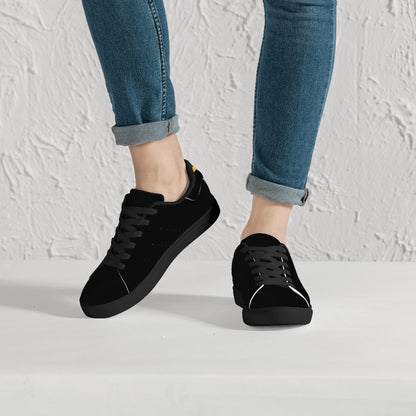 All-black Jamaica flag Ackee Walkers low top sneakers with black laces, black outsole and a green and gold Jamaican flag chevron at the heel