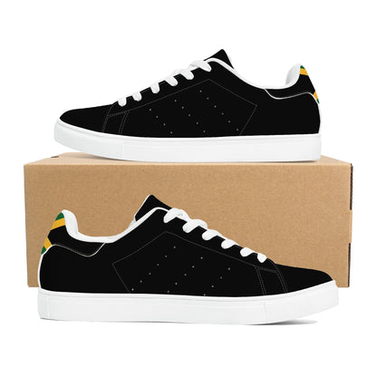 All-black Jamaica flag Ackee Walkers low top sneakers with black laces, black outsole and a green and gold Jamaican flag chevron at the heel