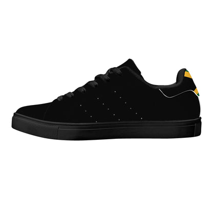 All-black Jamaica flag Ackee Walkers low top sneakers with black laces, black outsole and a green and gold Jamaican flag chevron at the heel